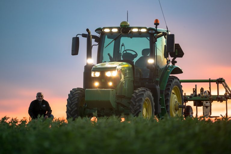 The pastel sunrise highlights GPS tractor operator Luis Garcia and the GPS tractor. Soon Echinacea purpurea will be harvested. Ephrata, Wash, July 2020. Photo: Darwin Hintz