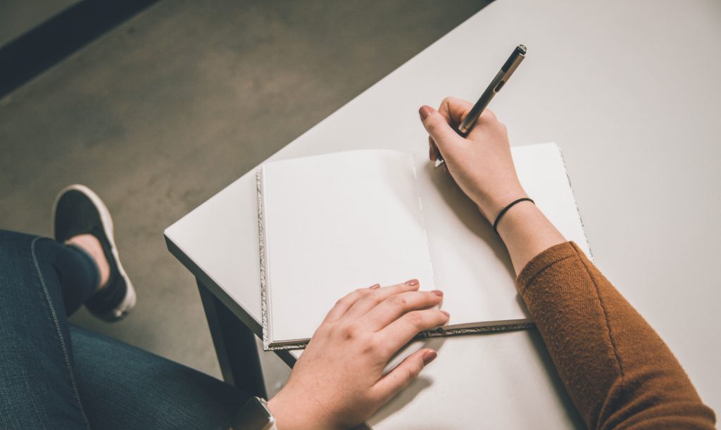A person writing on a notepad. Consider taking some quiet time to reflect on what brings meaning to your life, and how you can achieve it.