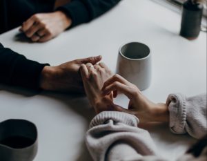 Two people holding hands at a dining table. Research shows good relationships keep us happier and healthier.