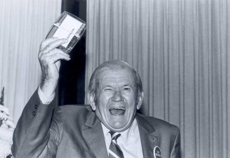 My father waving a container of Double X supplement at a Nutrilite sales rally. When I challenged him to show us his Double X, I expected to see a pocket carrier with a two-day supply, instead he pulled out an entire container to the delighted cheers of the ballroom audience. Los Angeles, Calif., circa 1965.