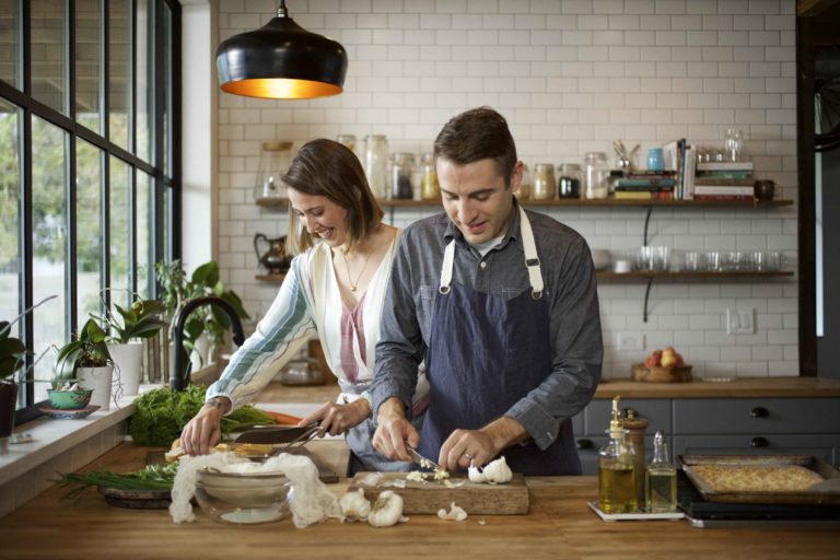 A couple working together in the kitchen to prepare a feast. Holiday meals with family and friends are a great time to add more plant-based dishes to the menu.