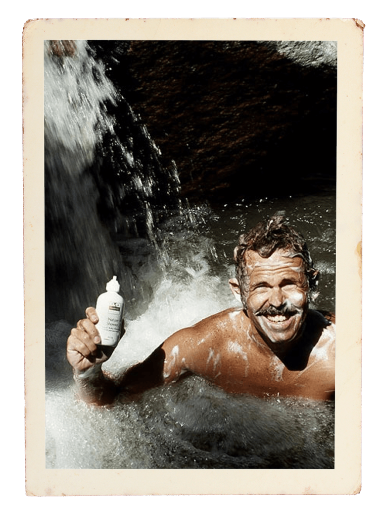 Dr Sam washing his hair in a waterfall with a Nutrilite product from the 70s